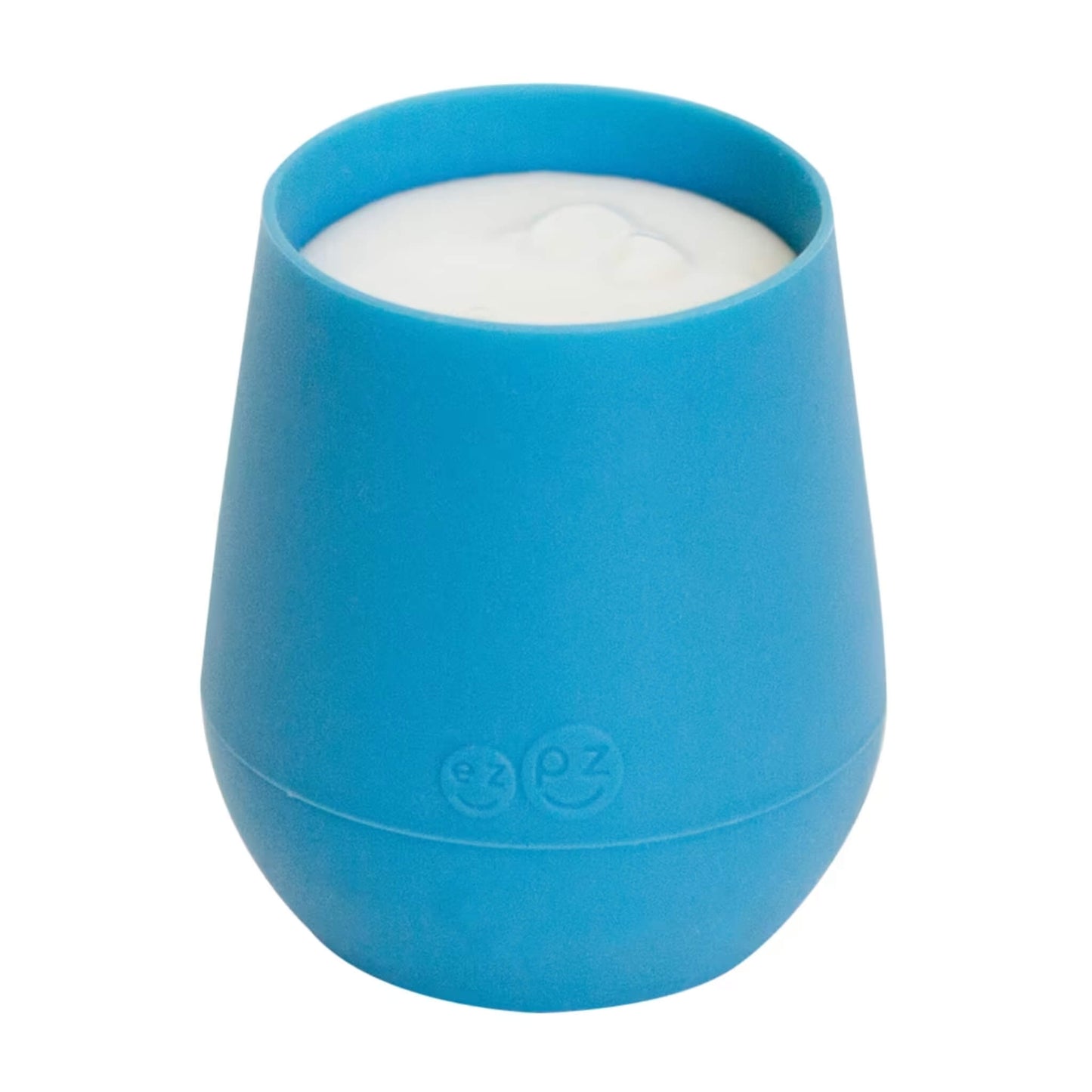Small blue silicone training cup filled with milk, shown close-up against a plain background.