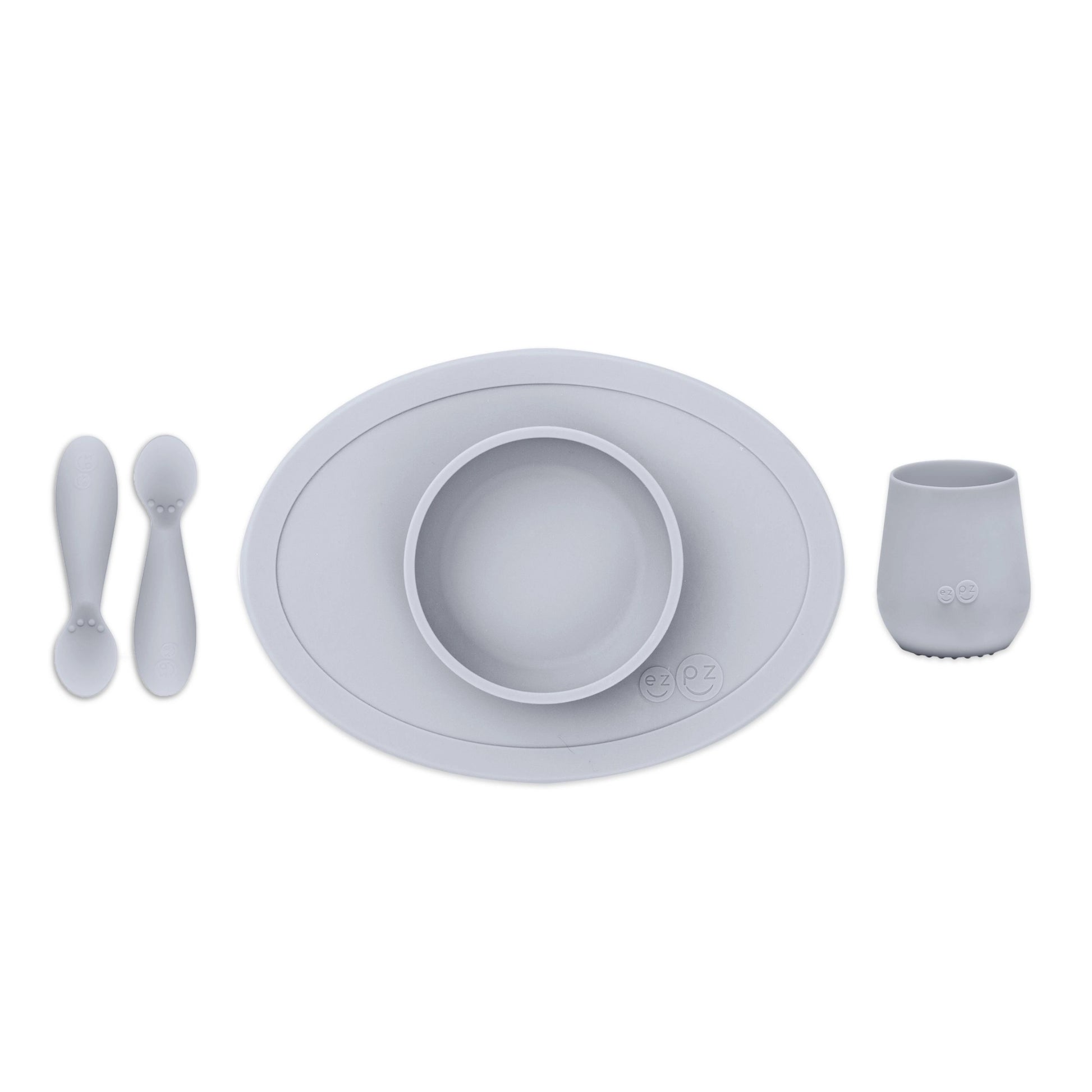 ezpz Tiny First Foods Set in pewter grey featuring a suction bowl, open cup and two soft silicone spoons for babies learning to self-feed.