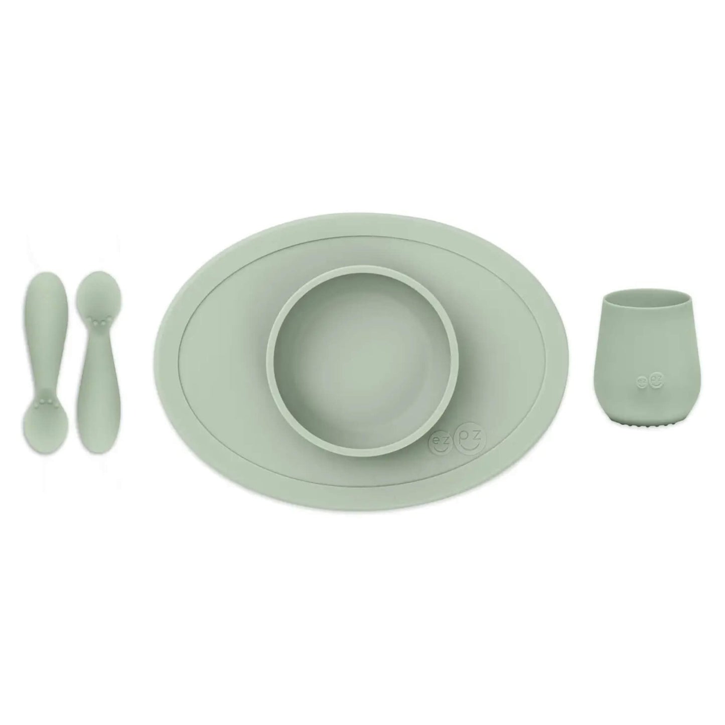 ezpz Tiny First Foods Set in sage green featuring a suction bowl, open cup and two soft silicone spoons for babies learning to self-feed.