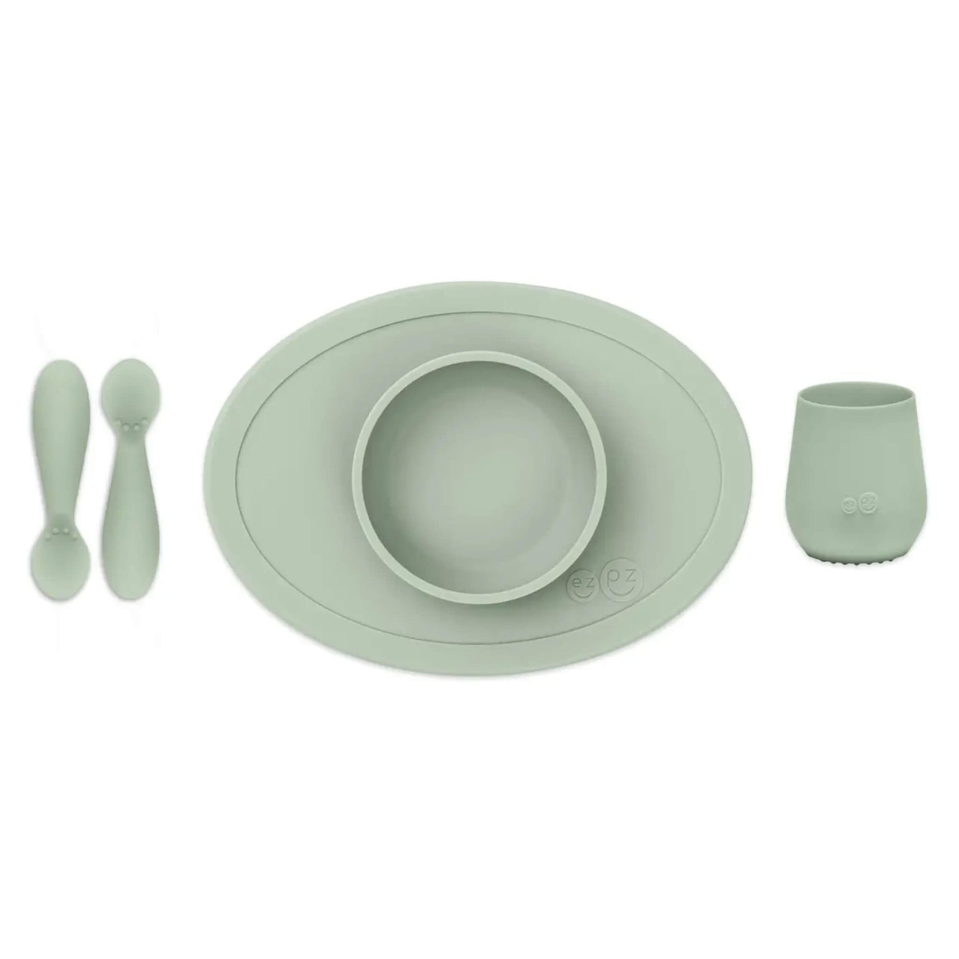 ezpz Tiny First Foods Set in sage green featuring a suction bowl, open cup and two soft silicone spoons for babies learning to self-feed.