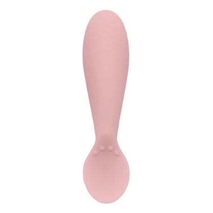 Single blush pink silicone infant training spoon with shallow head and small textured bumps on the handle.
