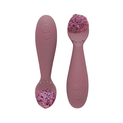 Pair of mauve silicone training spoons, each filled with a serving of purple baby food, shown close-up.