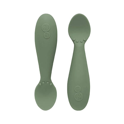 Ezpz Tiny Spoons in olive green, a pair of silicone infant training spoons with shallow heads and textured bumps near the base.
