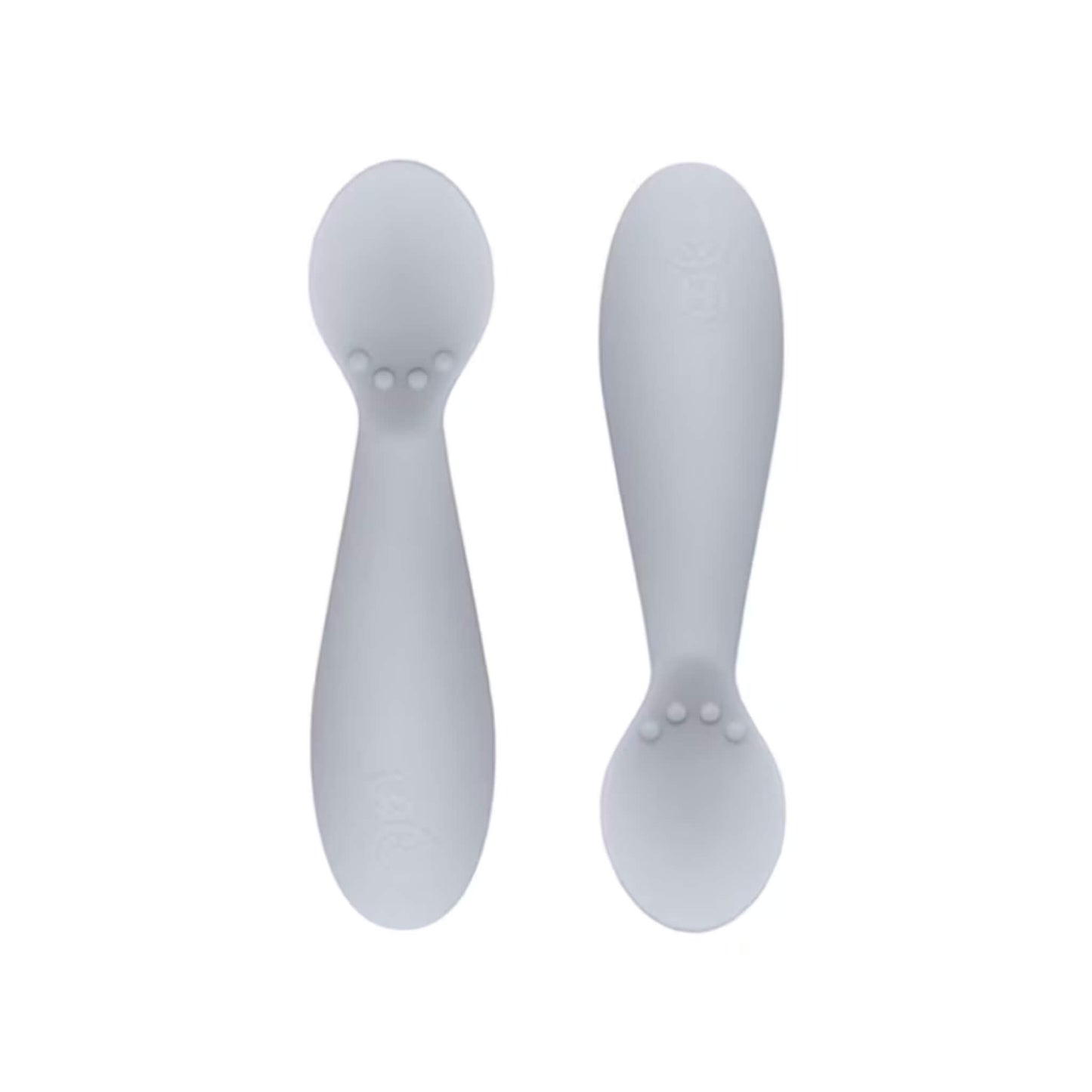 Ezpz Tiny Spoons in blush pink, a pair of silicone infant training spoons with shallow heads and textured bumps near the base.