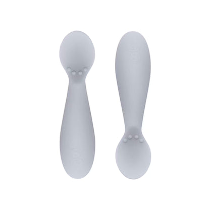 Ezpz Tiny Spoons in blush pink, a pair of silicone infant training spoons with shallow heads and textured bumps near the base.