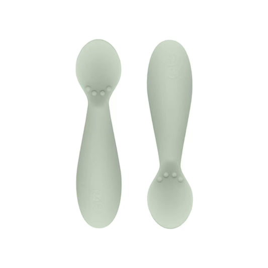 Ezpz Tiny Spoons in sage green, a pair of silicone infant training spoons with shallow heads and textured bumps near the base.