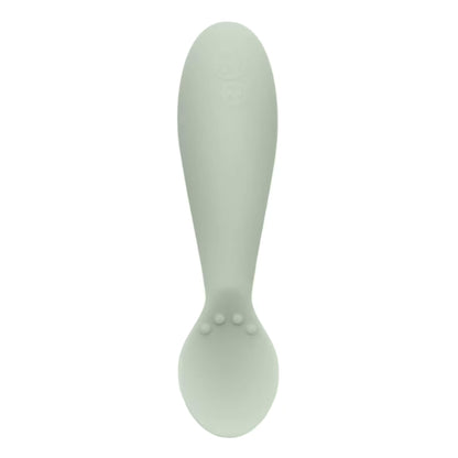 Single sage green silicone infant training spoon with shallow head and small textured bumps on the handle.