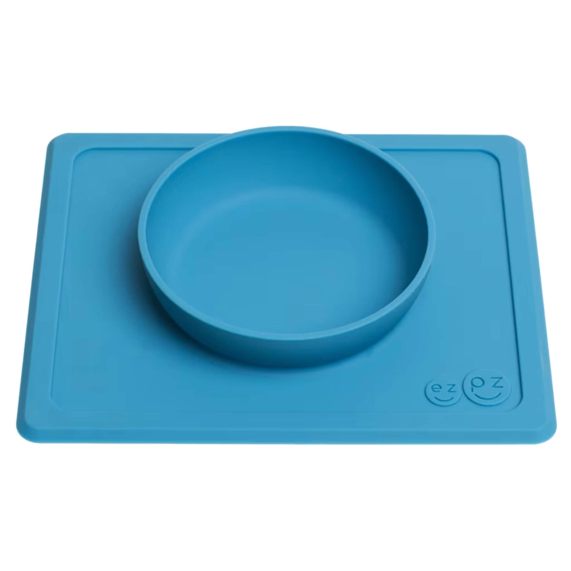 Side angle of the blue silicone ezpz Mini Bowl showing the raised circular bowl attached to the flat placemat base.
