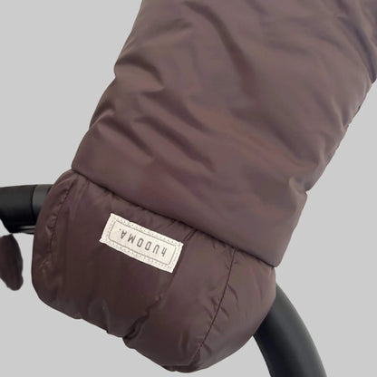 Detailed view of brown pram glove exterior fabric and hUDOMA brand label on the side of the stroller handle.