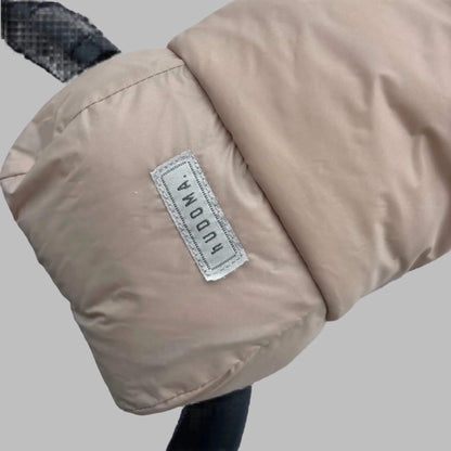 Close-up of beige pram glove exterior with stitched hUDOMA brand label on the side of a stroller handle.