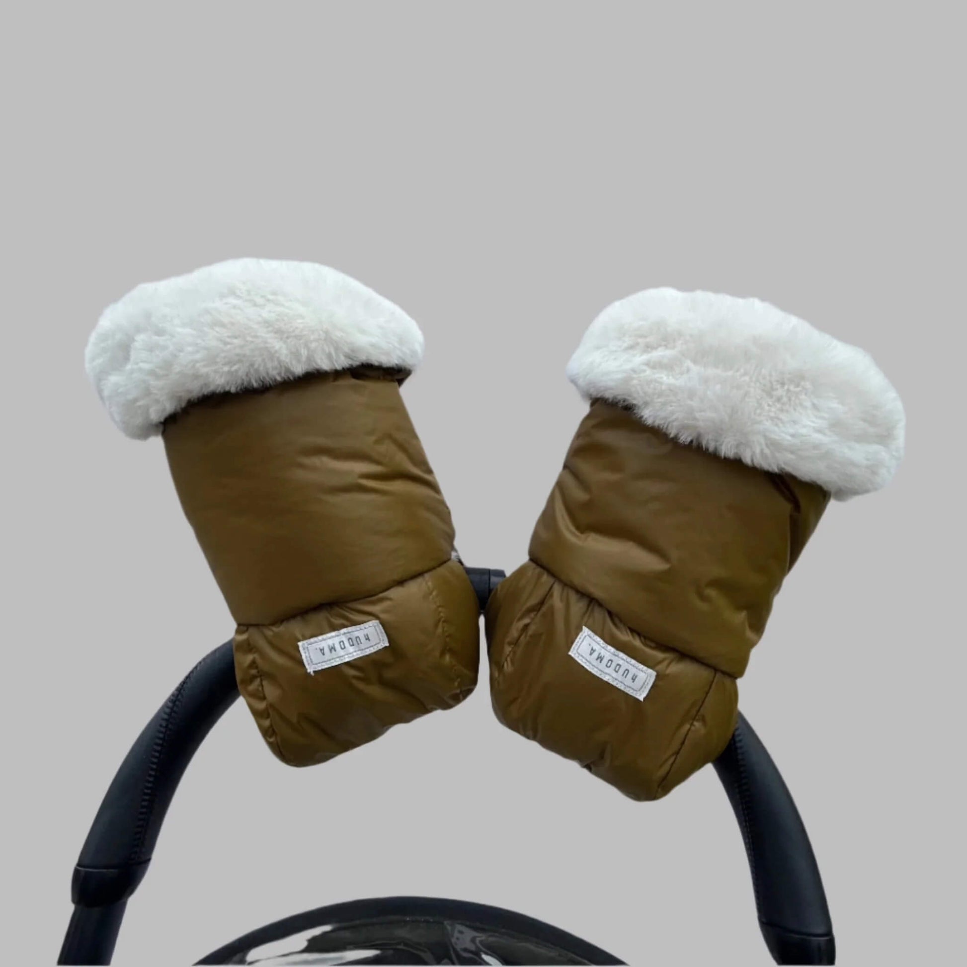 Pair of green pram gloves with white faux fur cuffs attached to a stroller handle, viewed from the front.