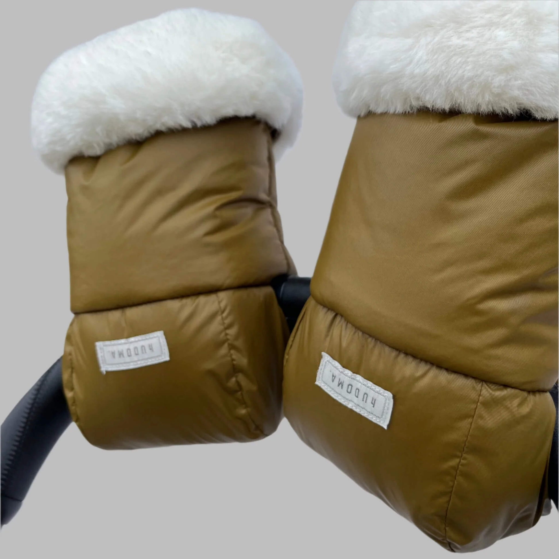 Angled view of green pram gloves on a stroller handle, highlighting fluffy faux fur trim and smooth weather-resistant outer fabric.