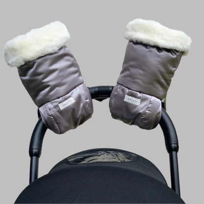 Pair of grey pram gloves with cream fleece lining fitted to a pushchair handle.
