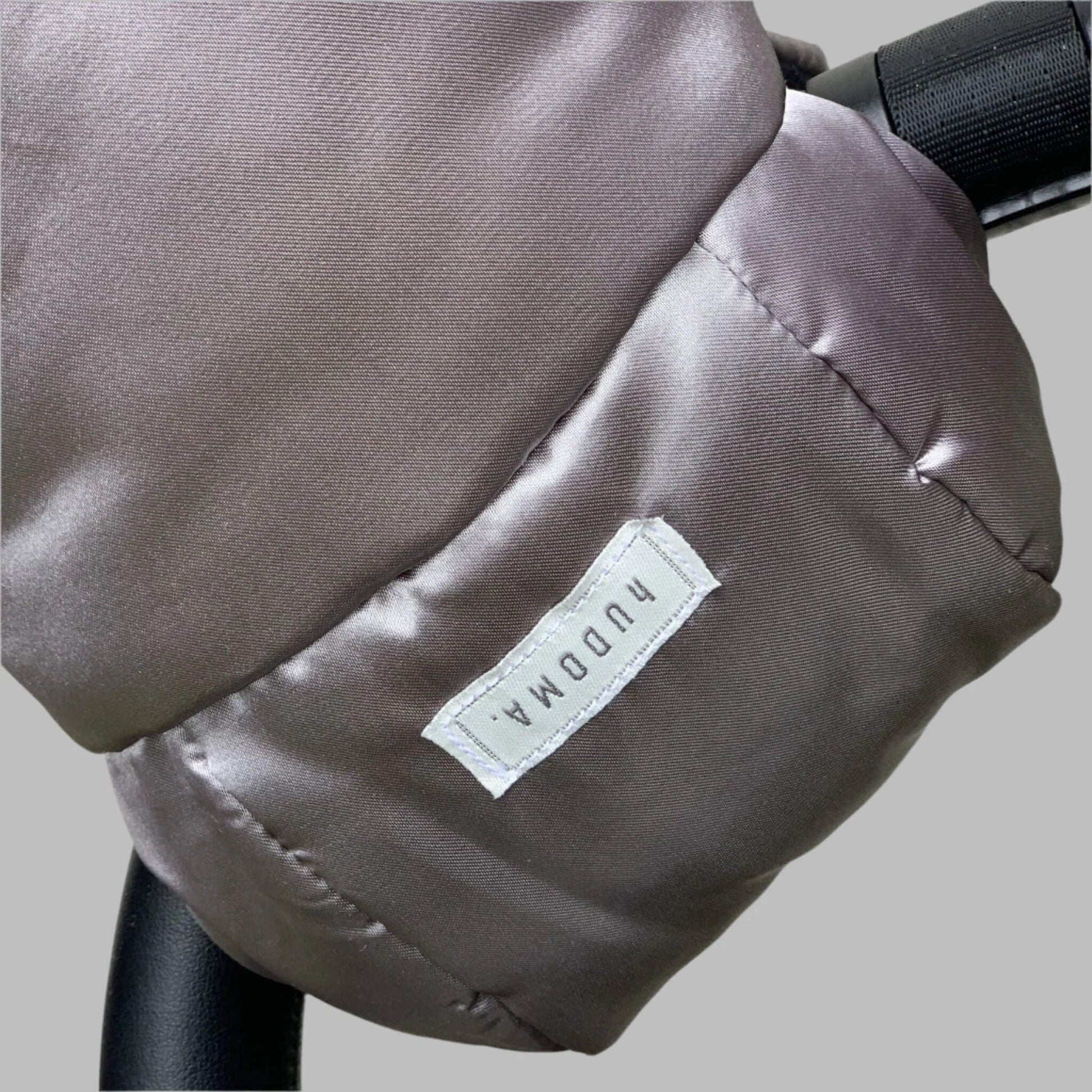 Close-up of pram glove fabric texture and stitched logo tag on the outer surface of the gloves.