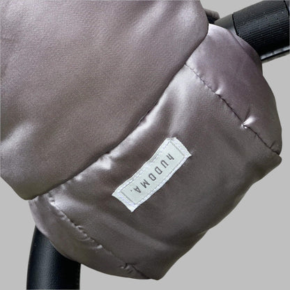 Close-up of pram glove fabric texture and stitched logo tag on the outer surface of the gloves.