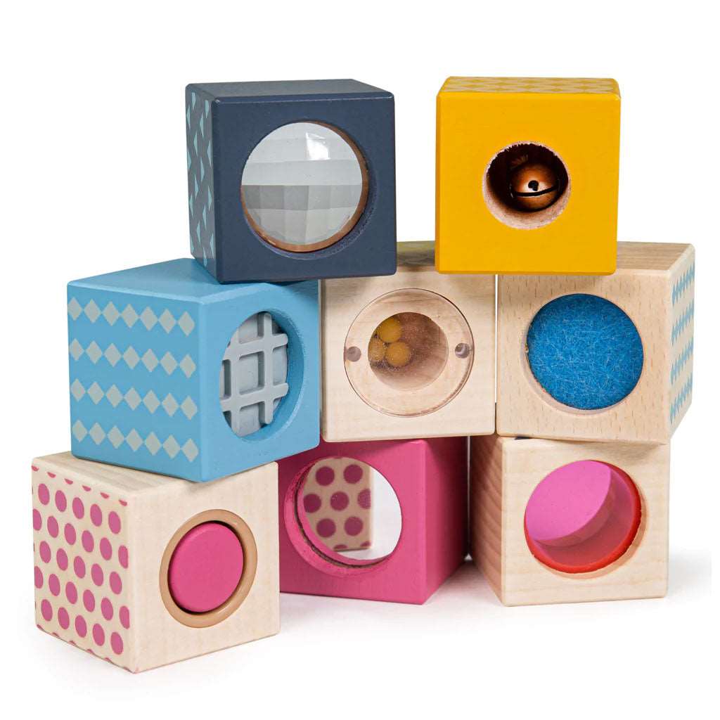 FSC 100% Sensory Blocks. The eight wooden blocks each have a different sensory experience including a jingly bell, a mirror, pink viewfinder, optical prism, scratchy felt, cylinder squeaker and rattle balls.
