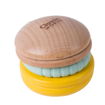 Close-up of a baby rattle shaped like a wooden macaroon, featuring a soft silicone teething ring and yellow base for sensory play.